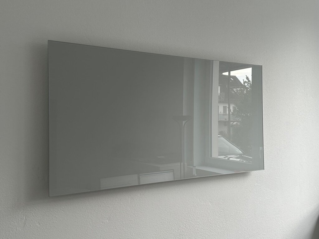 Lichtgraue rahmenlose Photonenheizung Glasheizung in modernem Raum.